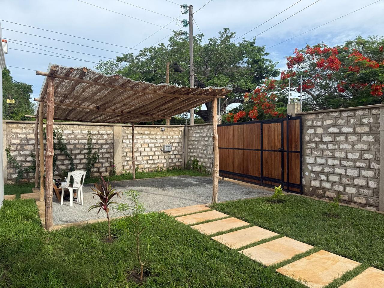 Villa Mawaka thatched carport with paving-stone path and flamboyant tree